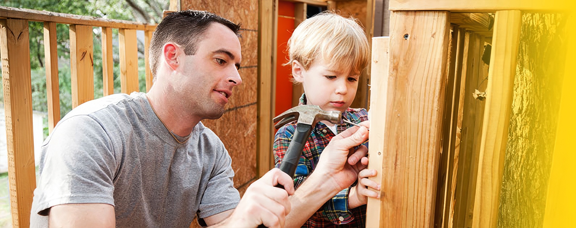 Das Bild zeigt einen Vater, der mit seinem Sohn einen Nagel einschl&auml;gt.